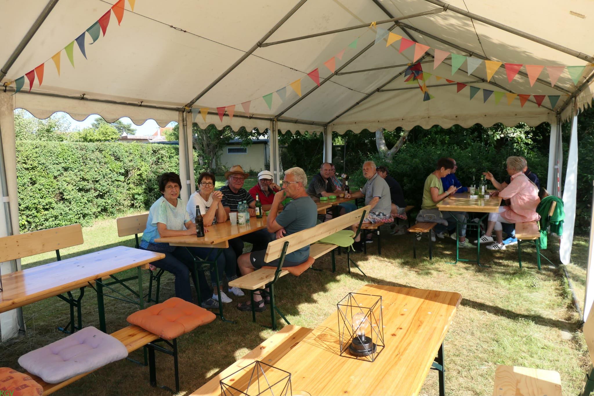Viele Gäste sitzen gemeinsam unter dem geschmückten Festzelt