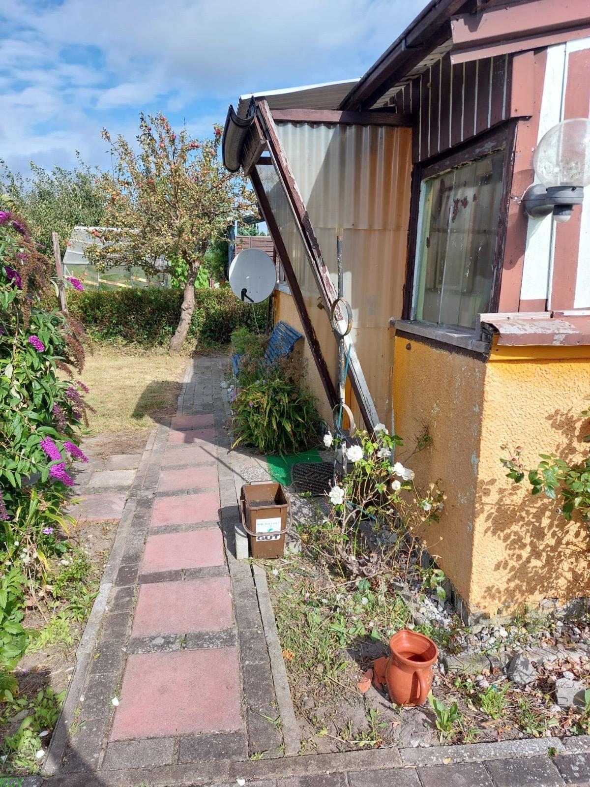 Seitenansicht der Laube mit Vordach und Gartenweg