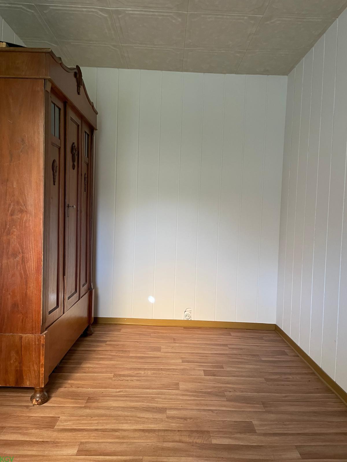 Zimmer mit Laminatboden und Kleiderschrank